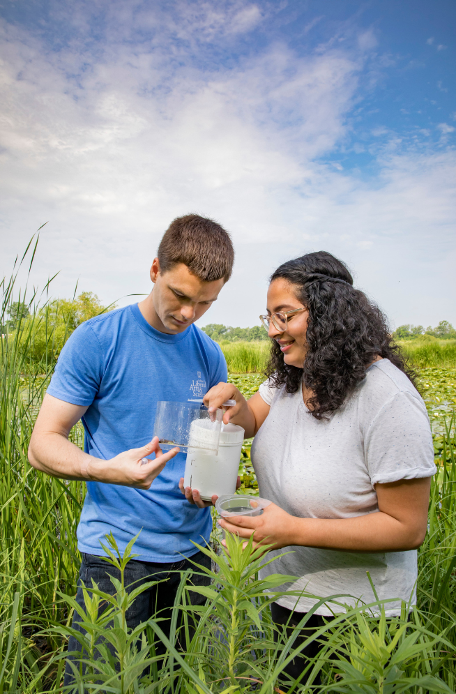 two students in field doing on site testing